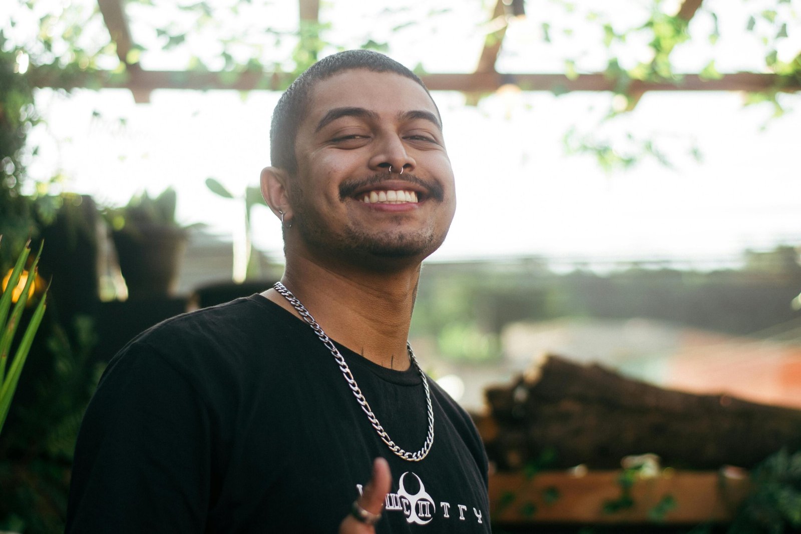 Cheerful man outdoors wearing a chain necklace and black t-shirt.